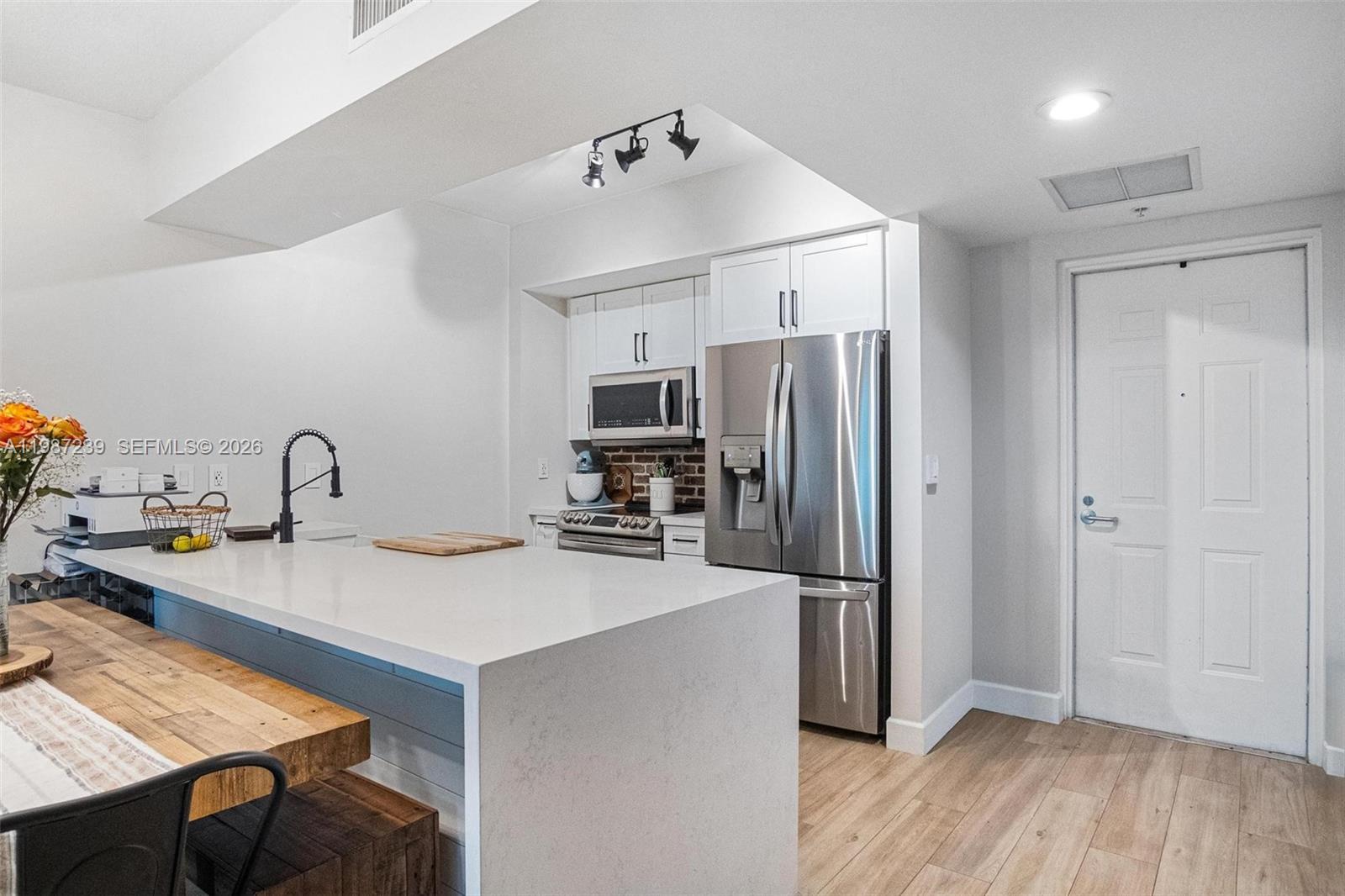 A modern kitchen features white cabinetry, stainless steel appliances, and a large quartz island — 7290 SW 90th St # 202, Miami FL 33156, MIAMI, FL