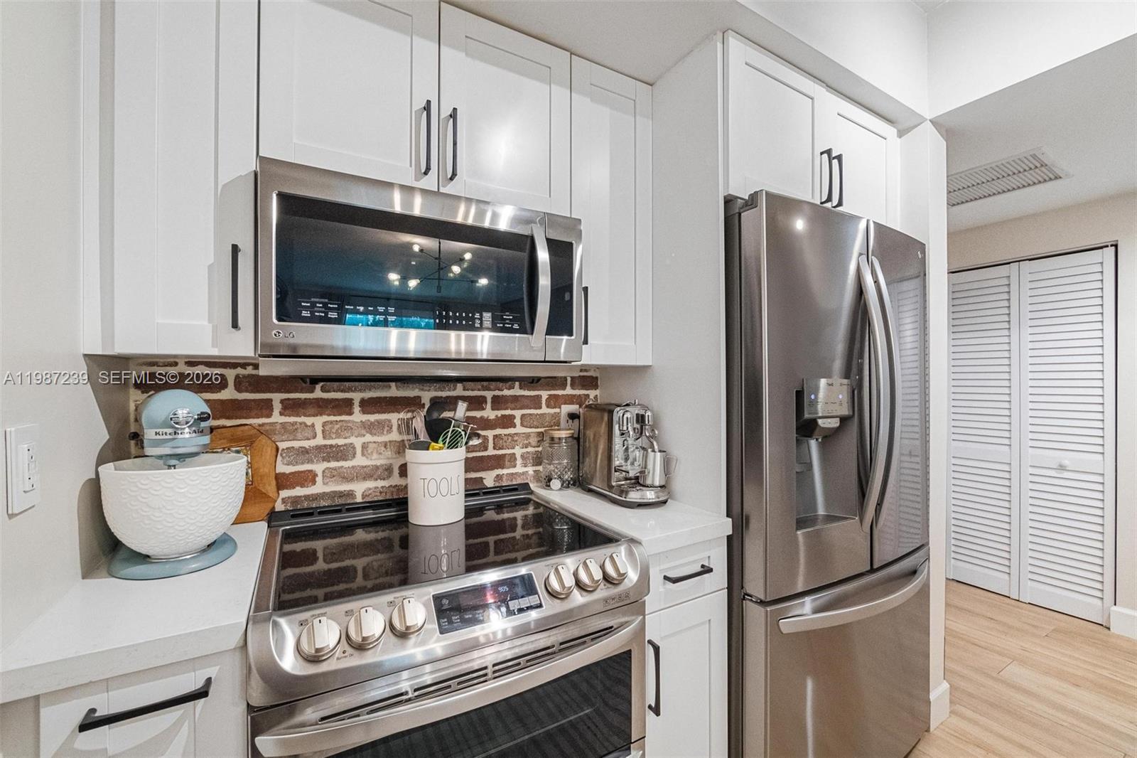 A kitchen features white cabinets, stainless steel appliances, and a brick backsplash — 7290 SW 90th St # 202, Miami FL 33156, MIAMI, FL