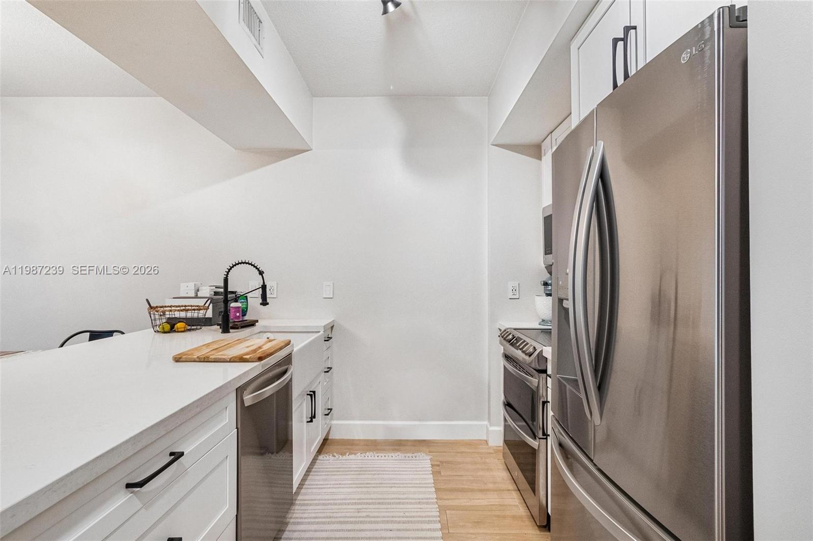 A modern kitchen features white cabinetry, stainless steel appliances, and a farmhouse sink — 7290 SW 90th St # 202, Miami FL 33156, MIAMI, FL