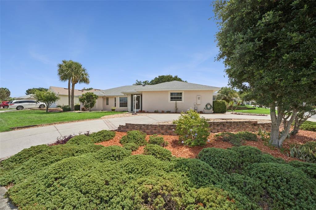 A single-story house with a concrete driveway, a retaining wall, and landscaped front yard — 21101 BRAVEHEART DRIVE, LEESBURG, FL