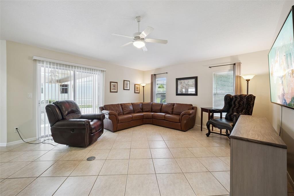 A living room features a brown sectional sofa, a recliner, tile floors, and a ceiling fan — 21101 BRAVEHEART DRIVE, LEESBURG, FL