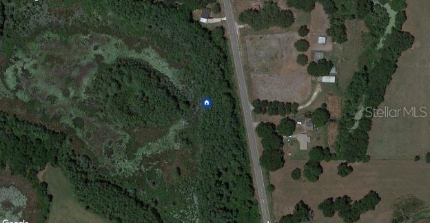 This is an aerial view of a wooded lot next to a road and rural properties — CR-33, GROVELAND, FL