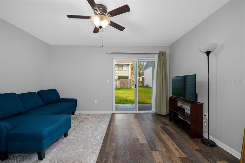 A living room features a blue sectional sofa, wood-look flooring, and a sliding glass door — 2132 SW 39TH DRIVE, GAINESVILLE, FL