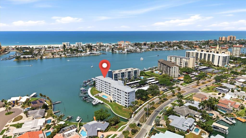 An aerial view shows a waterfront condominium building with a boat dock and pool — 610 ISLAND WAY UNIT 607, CLEARWATER BEACH, FL