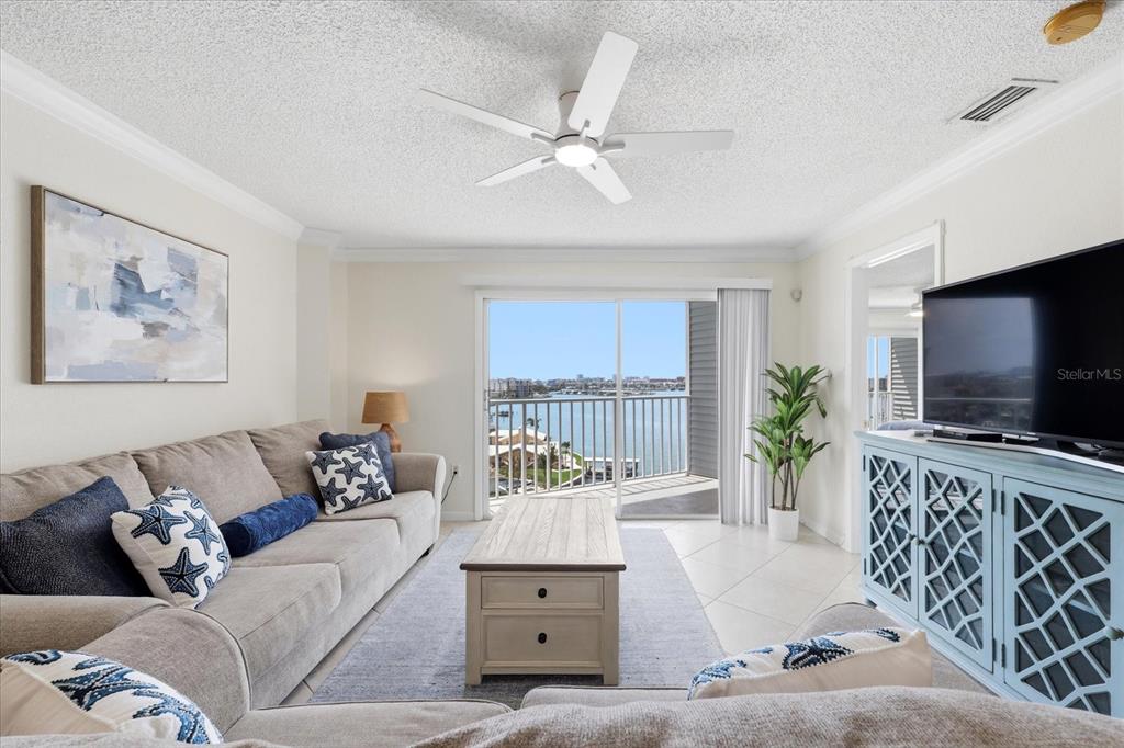 A living room features a grey sectional sofa, a coffee table, and a balcony view — 610 ISLAND WAY UNIT 607, CLEARWATER BEACH, FL