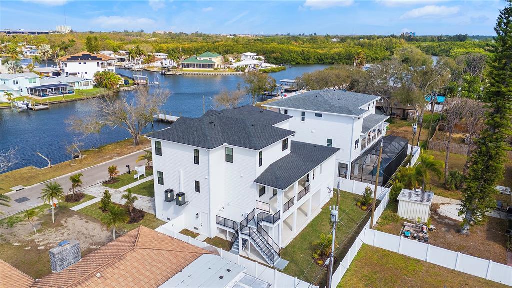 An aerial view shows a white multi-story house with a black roof near water — 220 90TH AVENUE NE, ST PETERSBURG, FL