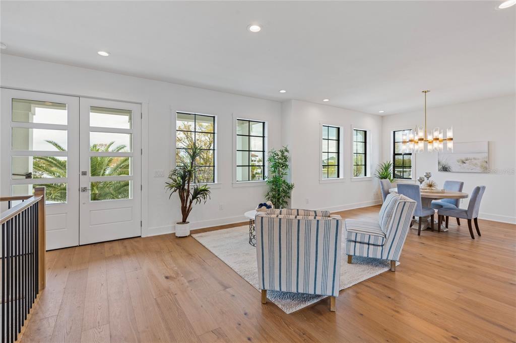 A bright living and dining area features white walls, hardwood floors, and large windows — 220 90TH AVENUE NE, ST PETERSBURG, FL