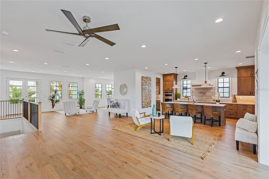 A spacious open-concept living and kitchen area features light wood flooring and a ceiling fan — 220 90TH AVENUE NE, ST PETERSBURG, FL
