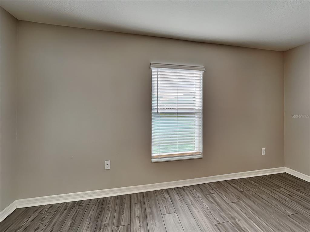 An empty room features gray walls, wood-look flooring, white trim, and a single window — 304 KENSINGTON VIEW DRIVE, WINTER HAVEN, FL