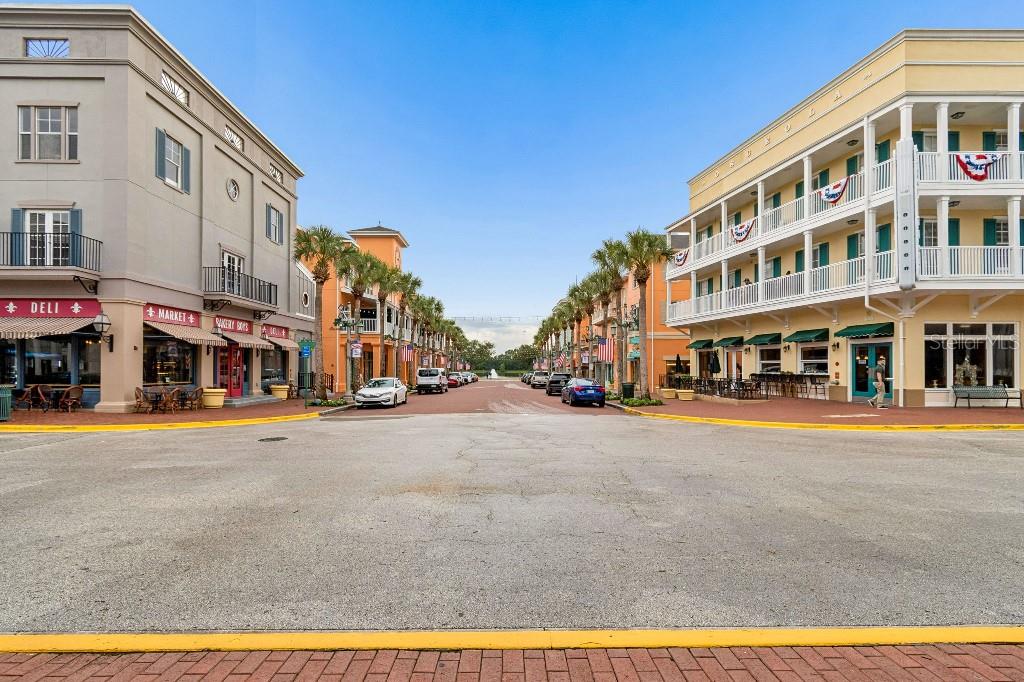 A street view of a commercial plaza with multi-story buildings, storefronts, and palm trees — 600 MARKET STREET UNIT 230, CELEBRATION, FL