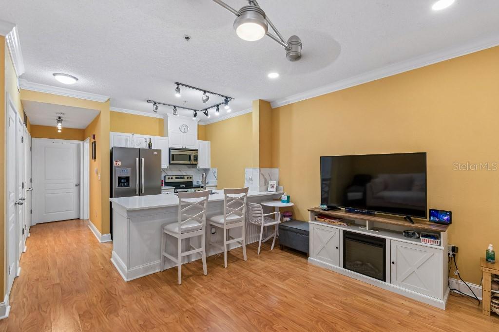 A kitchen with white cabinets and a breakfast bar opens into a living area — 600 MARKET STREET UNIT 230, CELEBRATION, FL