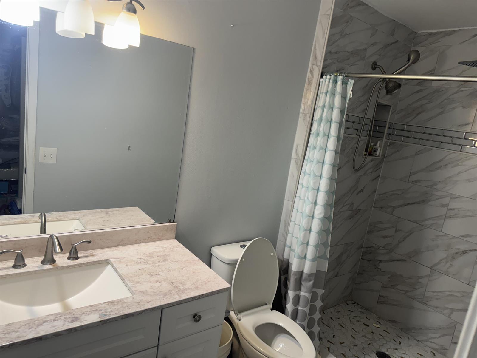 A bathroom features a vanity with a stone countertop, a toilet, and a tiled shower — 1234 White Pine Drive, Wellington FL 33414, WELLINGTON, FL