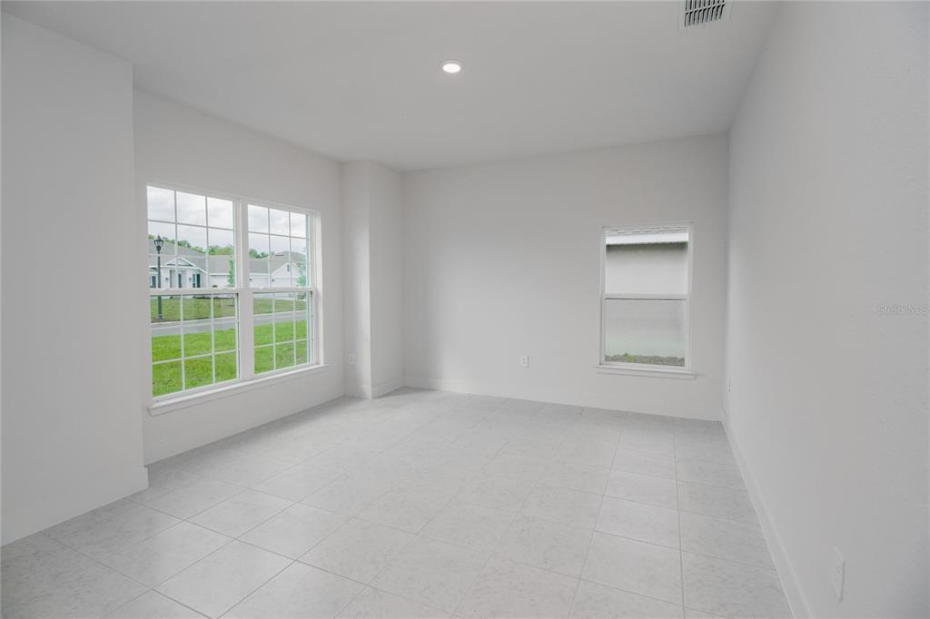 An empty room with white walls, light-colored tile flooring, and two windows — 1222 HICKORY NUT DRIVE, LAKE WALES, FL
