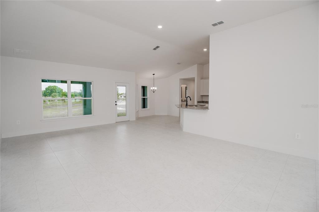 An open-concept living area with white tile flooring, recessed lighting, and a kitchen pass-through — 1222 HICKORY NUT DRIVE, LAKE WALES, FL