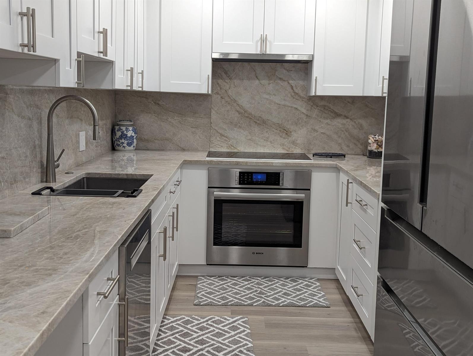 A modern kitchen features white cabinets, stainless steel appliances, and stone countertops with a matching backsplash — 2840 S Ocean Boulevard # 3230, Palm Beach FL 33480, PALM BEACH, FL