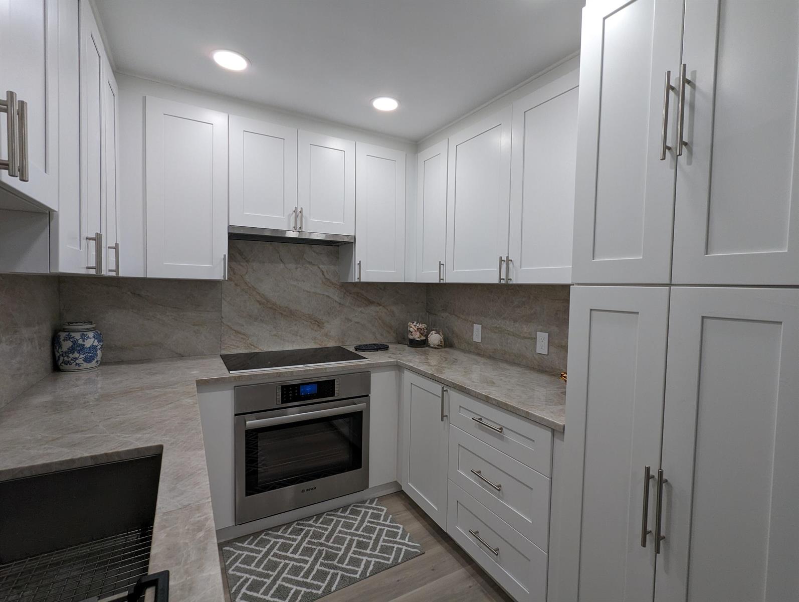 A kitchen features white shaker cabinets, stone countertops, a stainless steel oven, and a backsplash — 2840 S Ocean Boulevard # 3230, Palm Beach FL 33480, PALM BEACH, FL