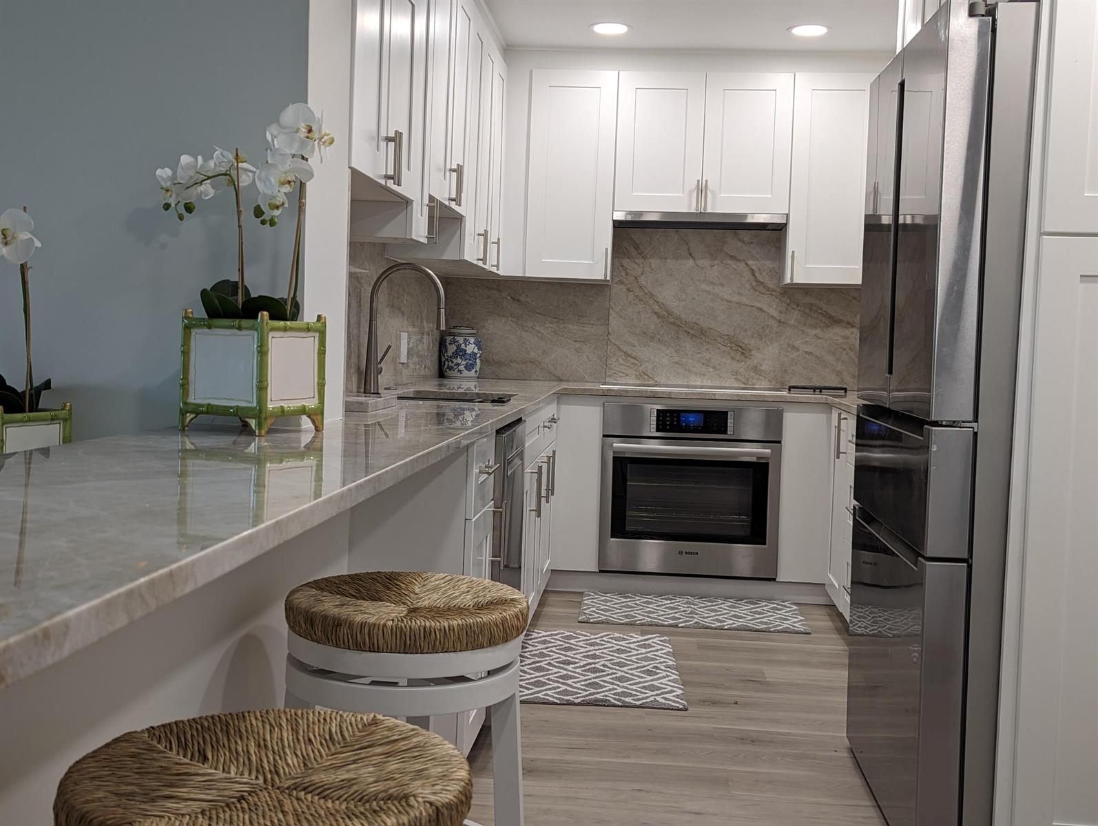 A modern kitchen features white cabinets, stainless steel appliances, and a stone countertop breakfast bar — 2840 S Ocean Boulevard # 3230, Palm Beach FL 33480, PALM BEACH, FL