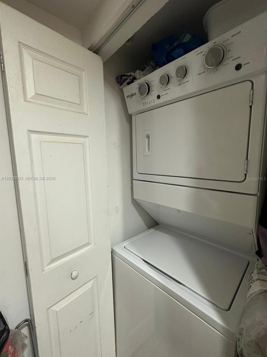 A white stacked Whirlpool washer and dryer unit sits inside a small closet — 3232 SW 22nd Ter # 1607, Miami FL 33145, MIAMI, FL