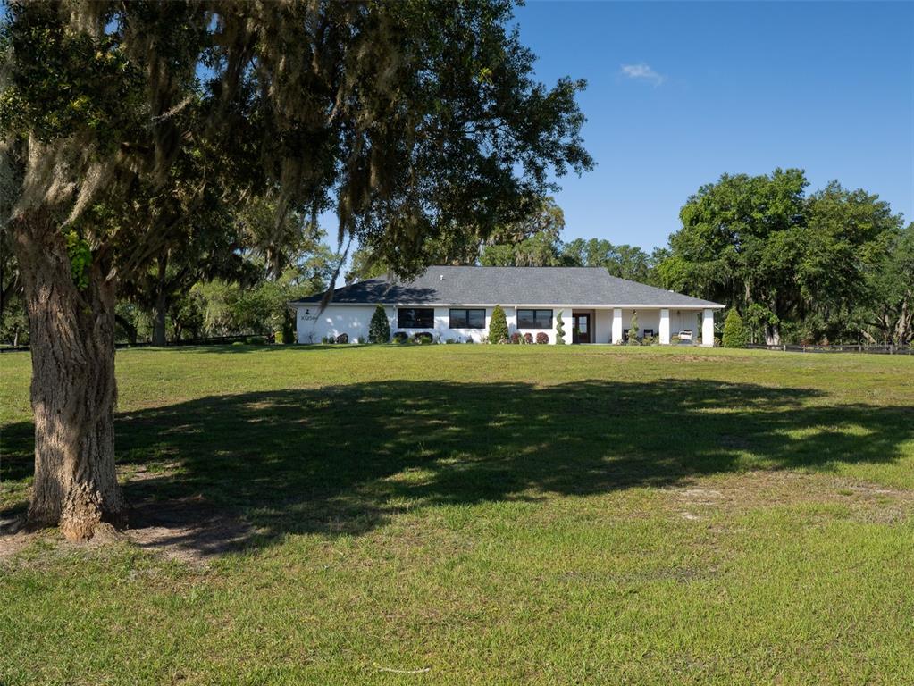 A white single-story house with a dark roof sits on a large grassy lot — 10250 NW 76TH TERRACE, OCALA, FL