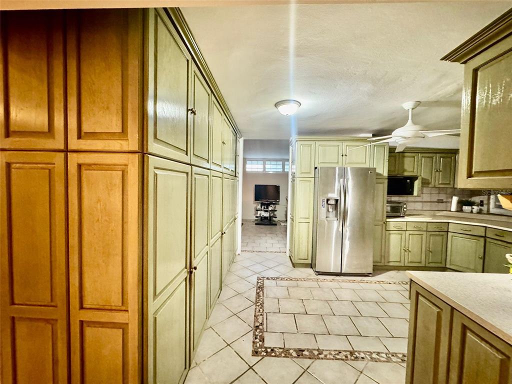 A kitchen features light green cabinetry, a stainless steel refrigerator, and tiled flooring — 2 St. ESTANCIAS DEL LAGO UNIT D-4, CAGUAS, PR
