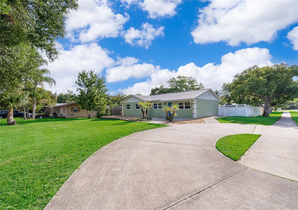 A single-story house with a green exterior and metal roof sits behind a concrete driveway — 437 OREGON AVENUE, ST CLOUD, FL