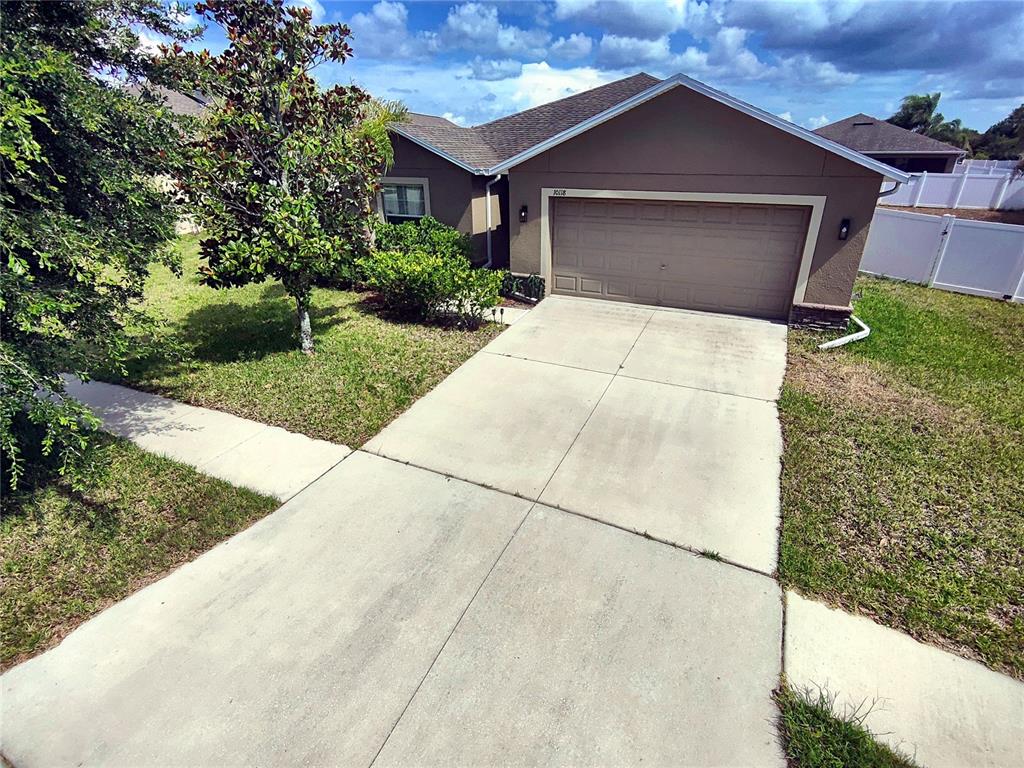 A single-story house with a tan stucco exterior, a two-car garage, and a concrete driveway — 10118 PENWOOD WAY, HUDSON, FL