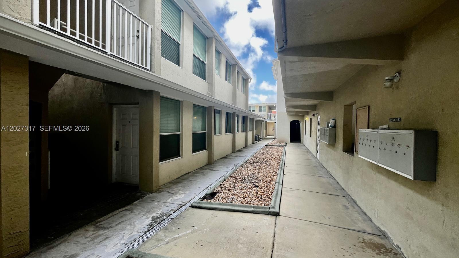 An outdoor walkway between two apartment buildings features a gravel garden bed and mailboxes — 1025 SW 7th Ave # 5, Miami FL 33130, MIAMI, FL