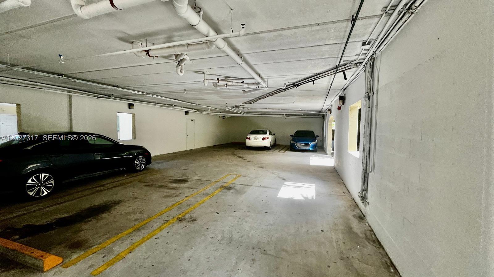 A covered parking garage features concrete walls, exposed ceiling pipes, and three parked cars — 1025 SW 7th Ave # 5, Miami FL 33130, MIAMI, FL