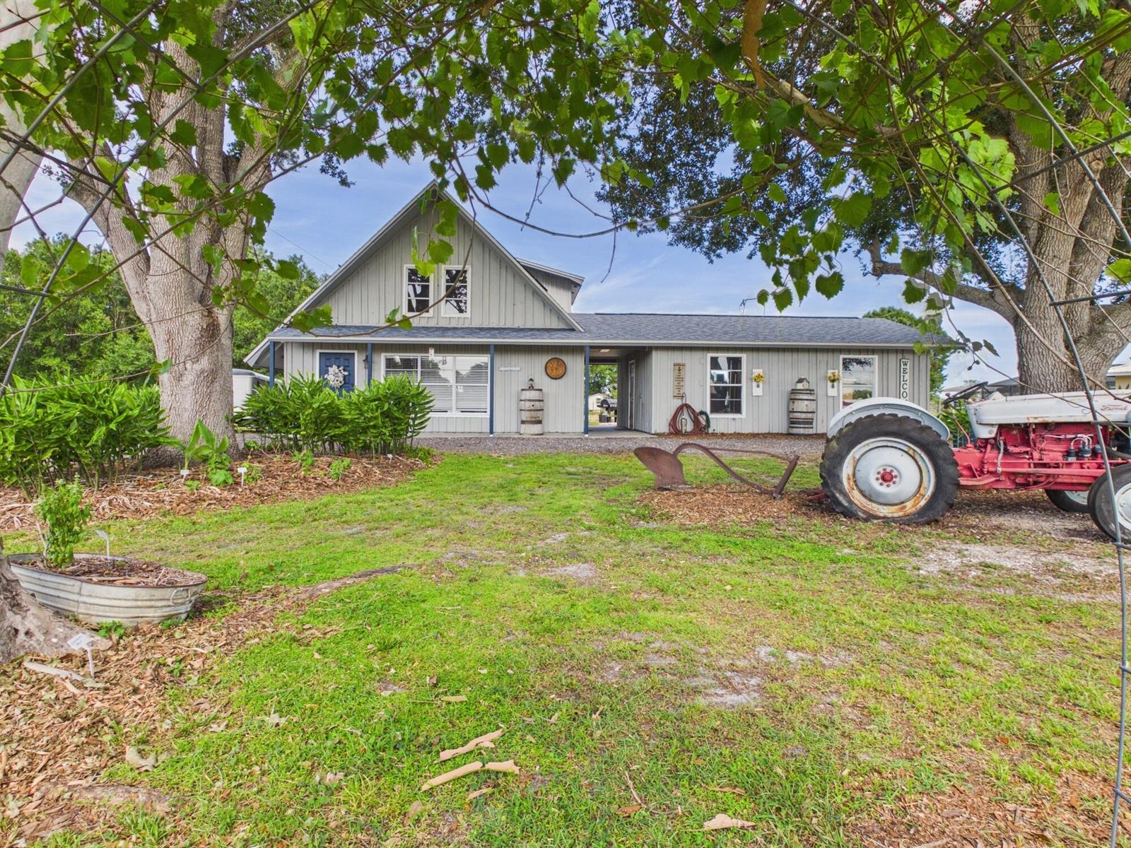 A gray house with a covered breezeway and a vintage tractor parked on the lawn — 136 SW 85th Avenue, Okeechobee FL 34974, OKEECHOBEE, FL
