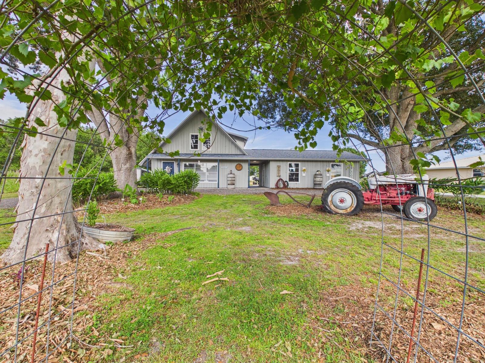 A gray house with a tractor and a metal trellis in the front yard — 136 SW 85th Avenue, Okeechobee FL 34974, OKEECHOBEE, FL