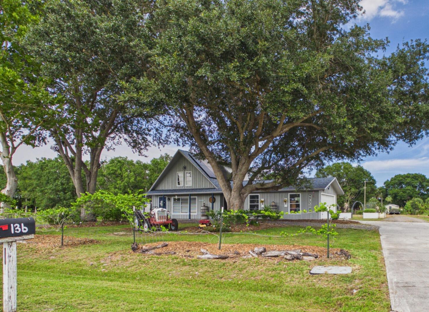 A gray house with a large oak tree and a vintage tractor in the front yard — 136 SW 85th Avenue, Okeechobee FL 34974, OKEECHOBEE, FL