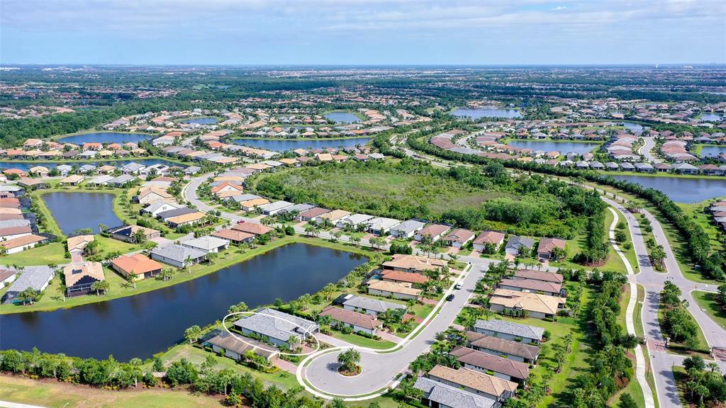 An aerial view shows a residential neighborhood with houses surrounding several ponds — 7636 KIRKLAND COVE, LAKEWOOD RANCH, FL