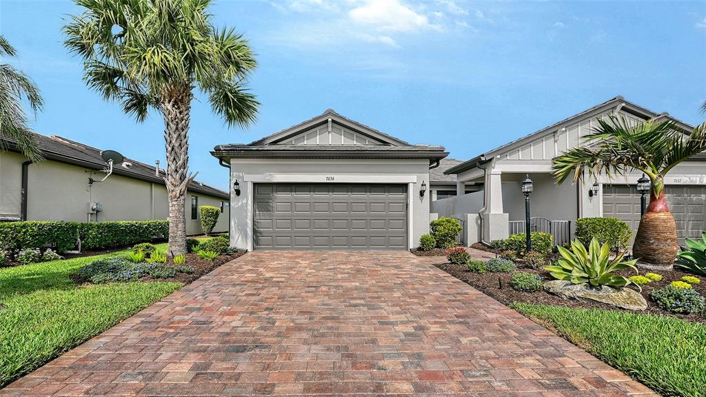 A single-story house with a paved driveway, a two-car garage, and palm trees — 7636 KIRKLAND COVE, LAKEWOOD RANCH, FL