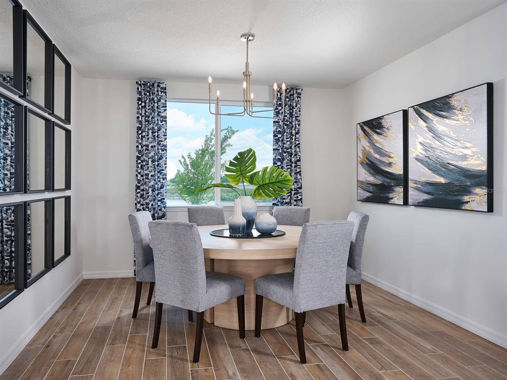 A dining room features a round wooden table, six gray chairs, and a modern chandelier — 14152 HARVEST PINES LANE, HUDSON, FL