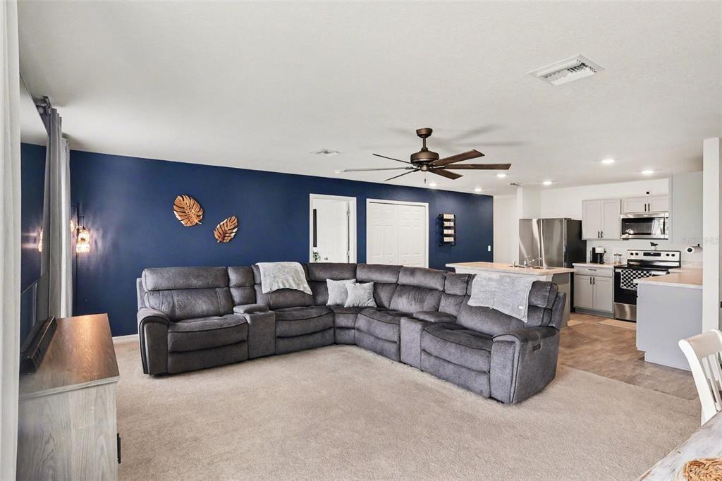 A living room with a dark blue accent wall, gray sectional sofa, and open kitchen — 1409 NE 4TH PLACE, CAPE CORAL, FL