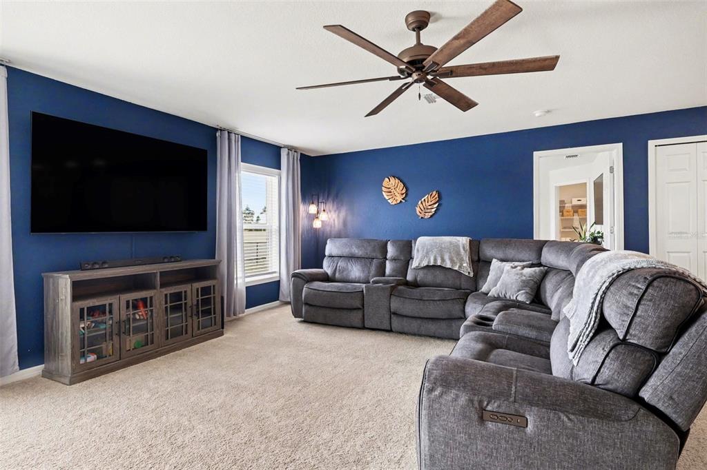 A living room features blue walls, a large gray sectional, and a television console — 1409 NE 4TH PLACE, CAPE CORAL, FL