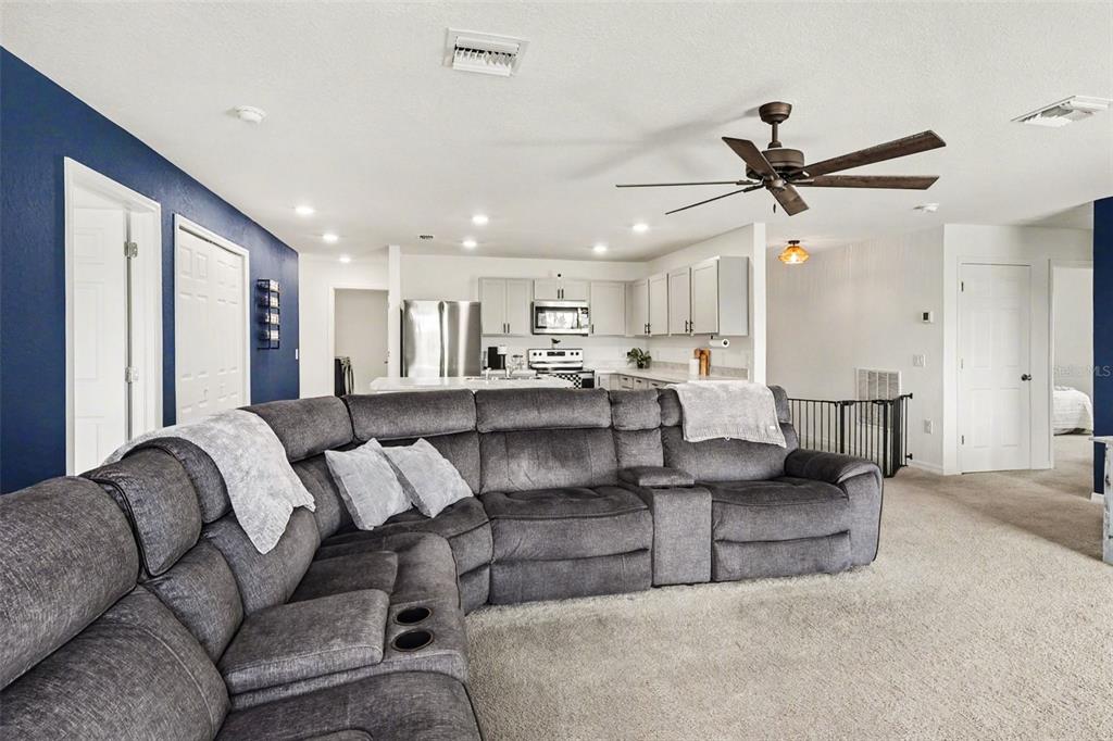 A large gray sectional sofa sits in a living room facing an open-concept kitchen — 1409 NE 4TH PLACE, CAPE CORAL, FL
