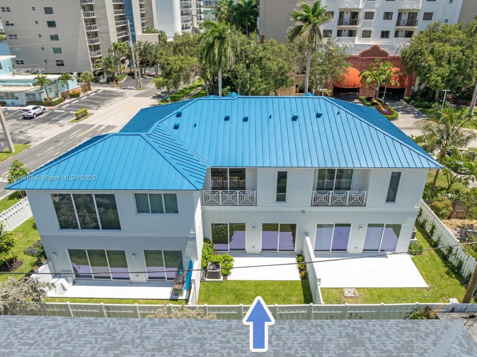 An aerial view shows the rear exterior of a two-story white house with a blue roof — 554 N Riverside Dr # B, Pompano Beach FL 33062, POMPANO BEACH, FL