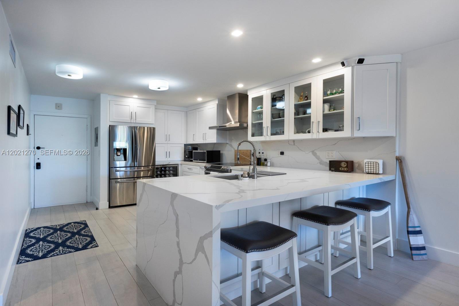 A modern kitchen features white cabinetry, marble-patterned countertops, a waterfall island, and stainless steel appliances — 6815 Edgewater Dr # 307, Coral Gables FL 33133, CORAL GABLES, FL