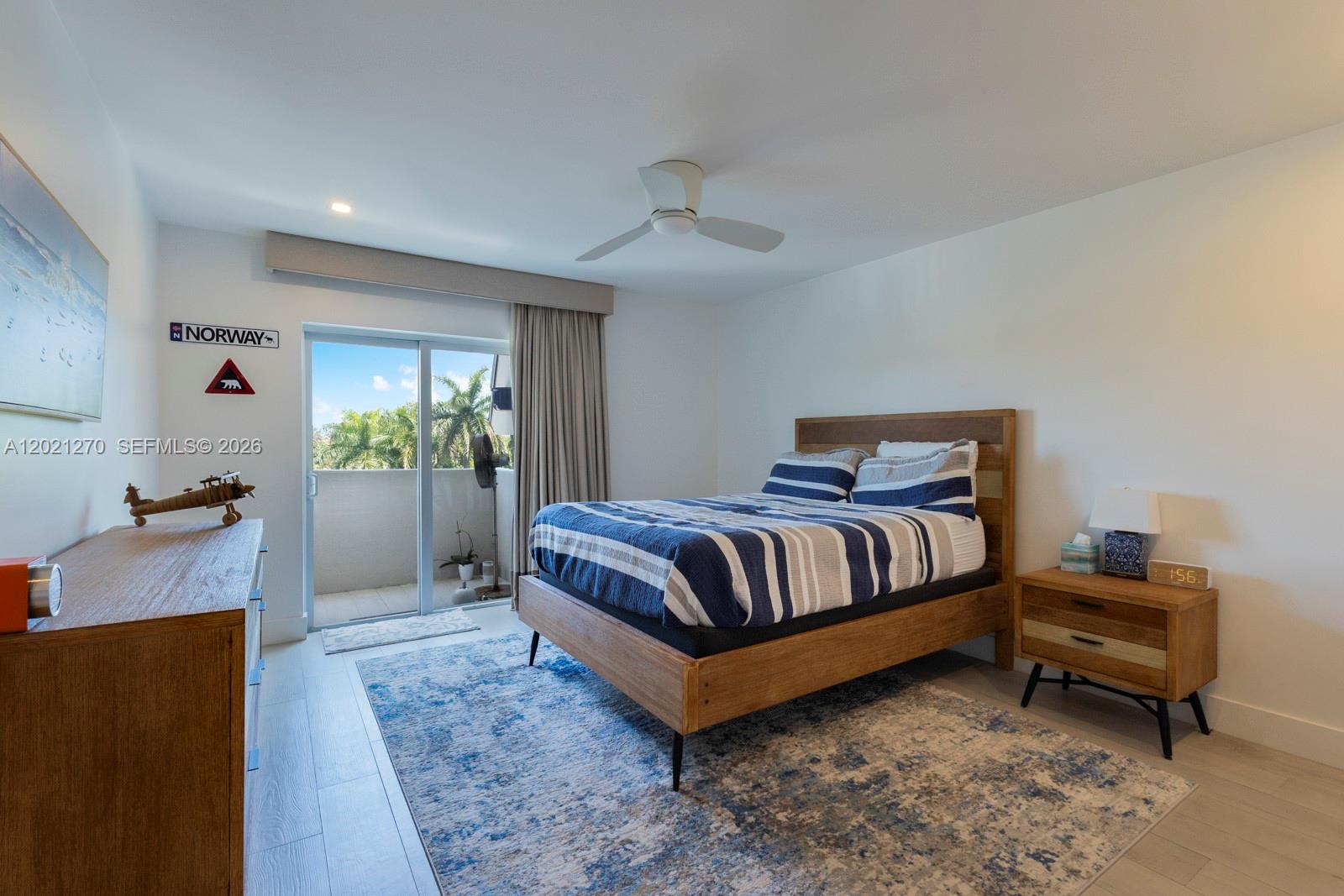 A bedroom features a wooden bed frame, a blue patterned rug, and a sliding glass door — 6815 Edgewater Dr # 307, Coral Gables FL 33133, CORAL GABLES, FL