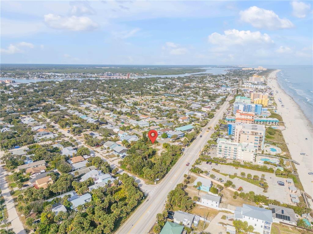 An aerial view shows a vacant lot marked with a red pin near the beach — 833 MARALYN AVENUE, NEW SMYRNA BEACH, FL
