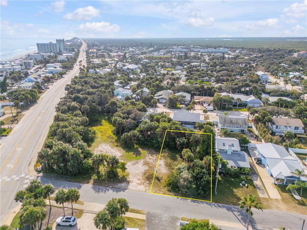 An aerial view shows a vacant, rectangular residential lot outlined in yellow near a coastal road — 833 MARALYN AVENUE, NEW SMYRNA BEACH, FL