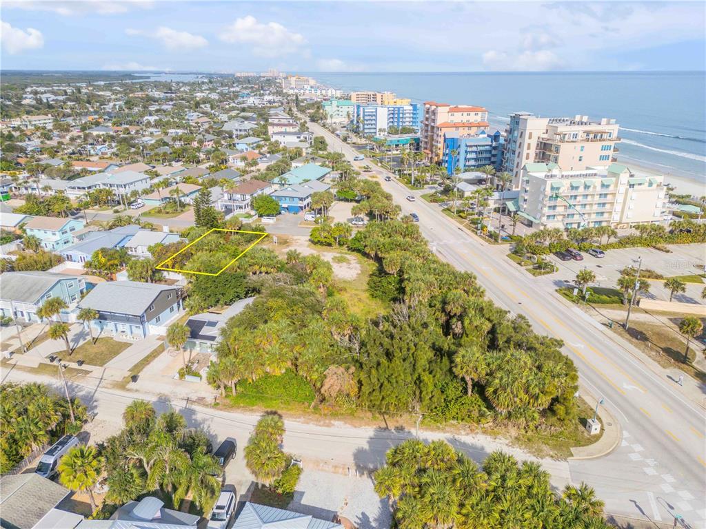 An aerial view shows a vacant, rectangular lot outlined in yellow near a coastal road — 833 MARALYN AVENUE, NEW SMYRNA BEACH, FL