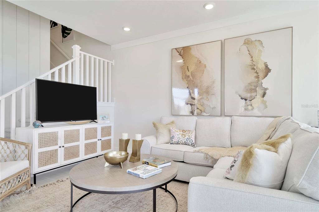 A living room features a white sofa, a round coffee table, and abstract wall art — 32062 ANCHOR POINT DRIVE, WESLEY CHAPEL, FL
