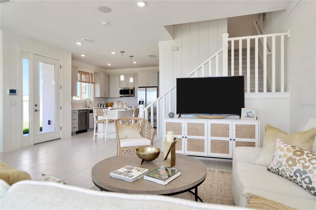 A bright open-concept living room and kitchen feature white cabinetry, tile floors, and a staircase — 32062 ANCHOR POINT DRIVE, WESLEY CHAPEL, FL