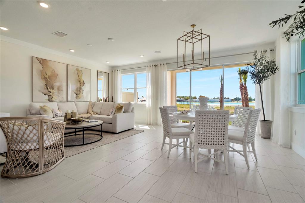 A bright open-concept living and dining area features light tile floors and large sliding doors — 32062 ANCHOR POINT DRIVE, WESLEY CHAPEL, FL