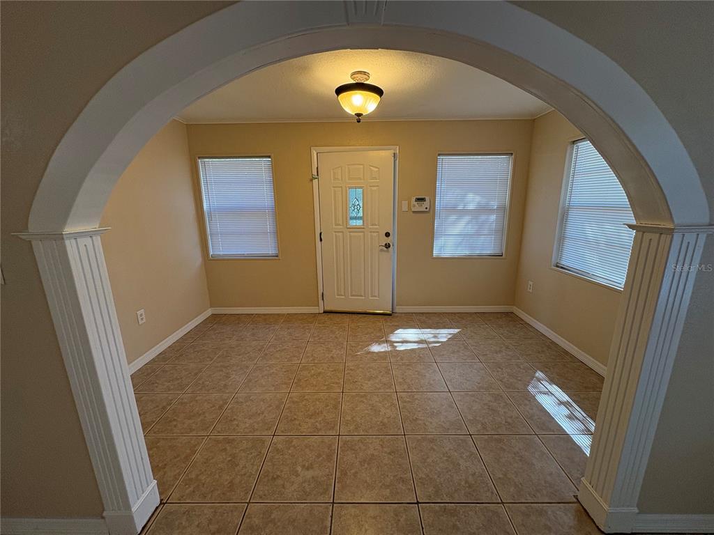 An entryway with beige tile flooring, three windows with blinds, and a white front door — 8351 WAKEFORD ROAD, LAKE WALES, FL