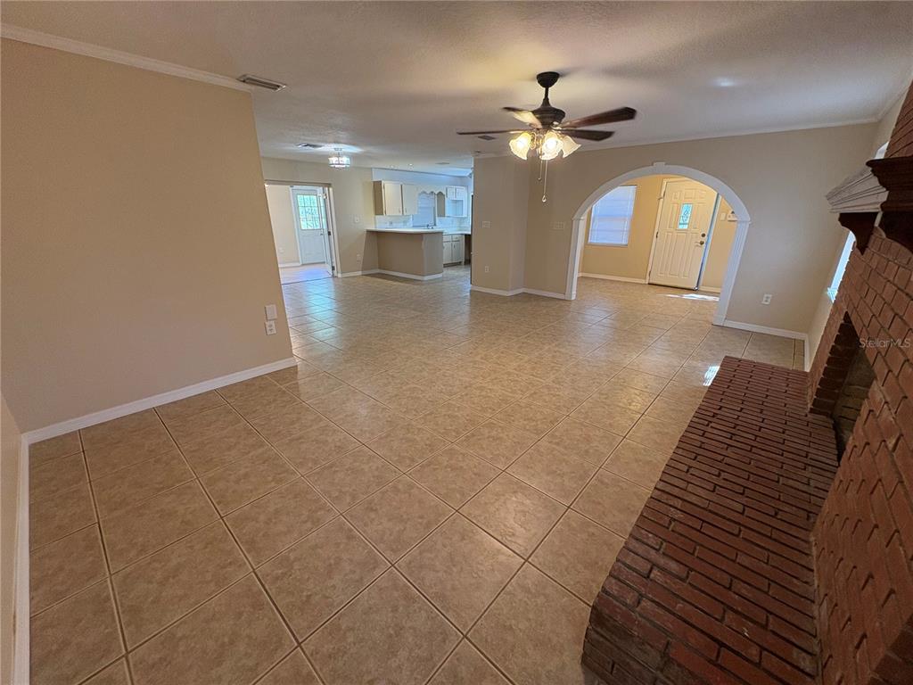 A spacious living area with tile flooring, a brick fireplace, and an arched entryway — 8351 WAKEFORD ROAD, LAKE WALES, FL