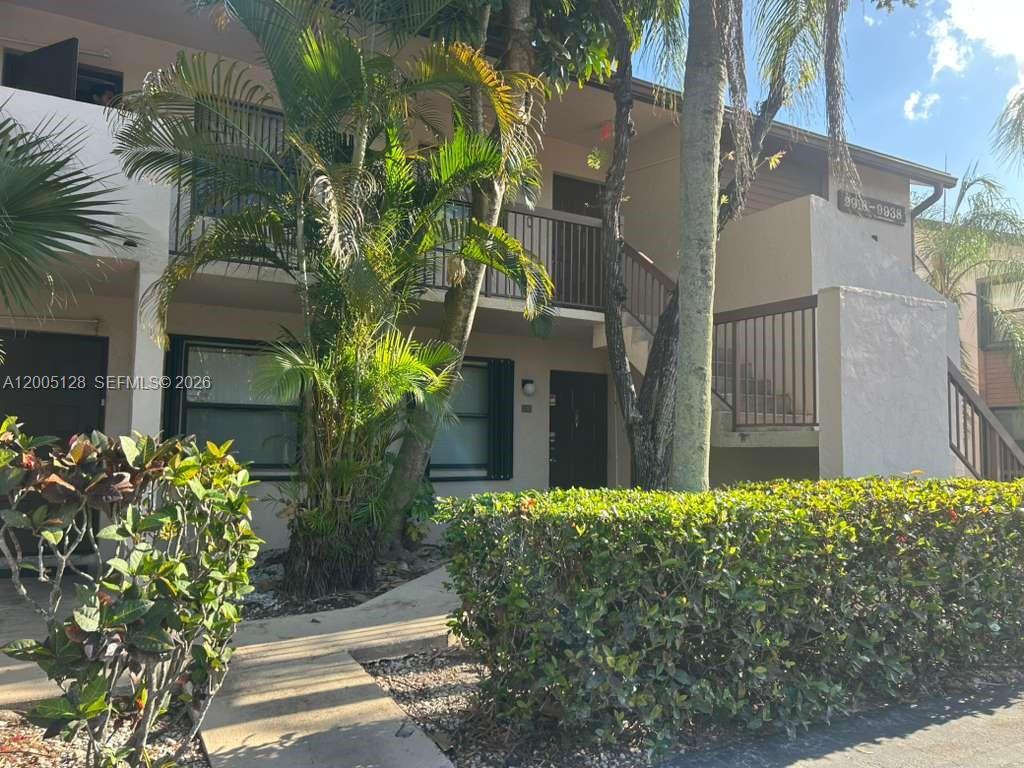A two-story apartment building exterior features a concrete walkway, palm trees, and a hedge — 9926 Nob Hill Ct # 9926, Sunrise FL 33351, SUNRISE, FL