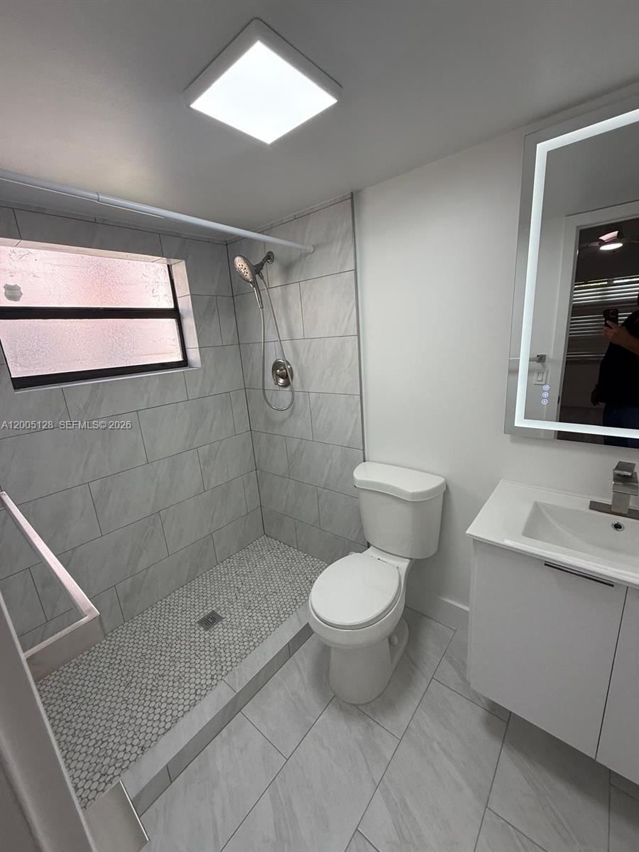 A modern bathroom features a walk-in shower with gray tile, a toilet, and a vanity — 9926 Nob Hill Ct # 9926, Sunrise FL 33351, SUNRISE, FL